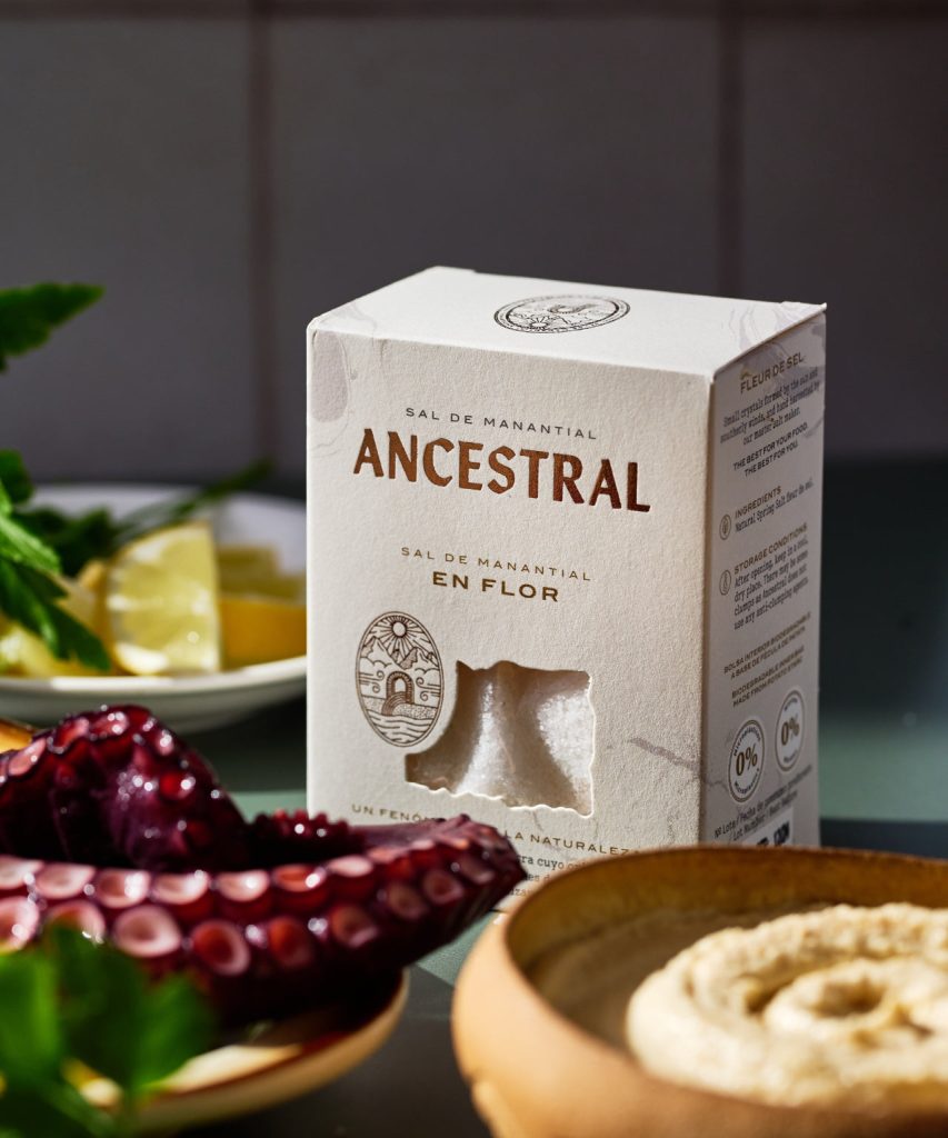 Ancestral Flor de Sal carton beside octopus, lemon and a bowl of salt