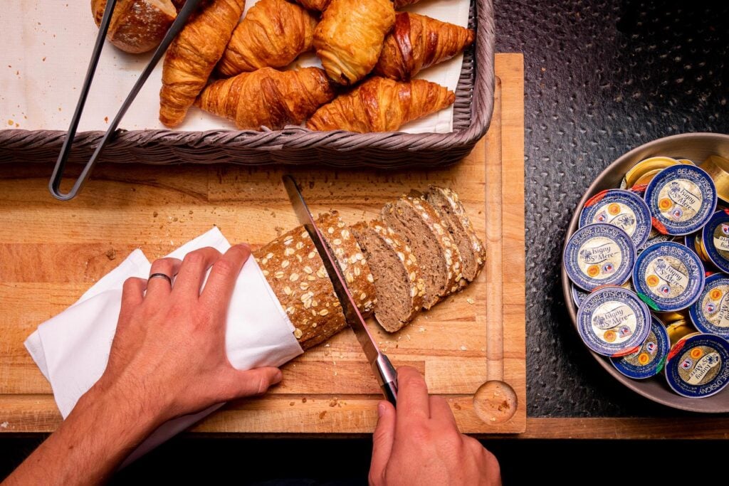 Individual Beurre d’Isigny butter portions beside freshly sliced bread and croissants