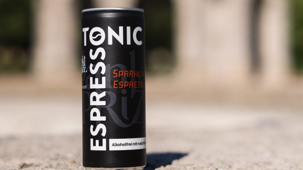 Espresso Tonic can by Sankt Sprizz and Mount Hagen in front of Munich architecture
