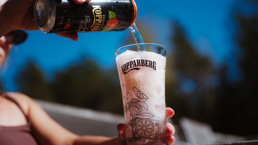 Kopparberg Strawberry and Lime cider being poured over ice into a branded glass